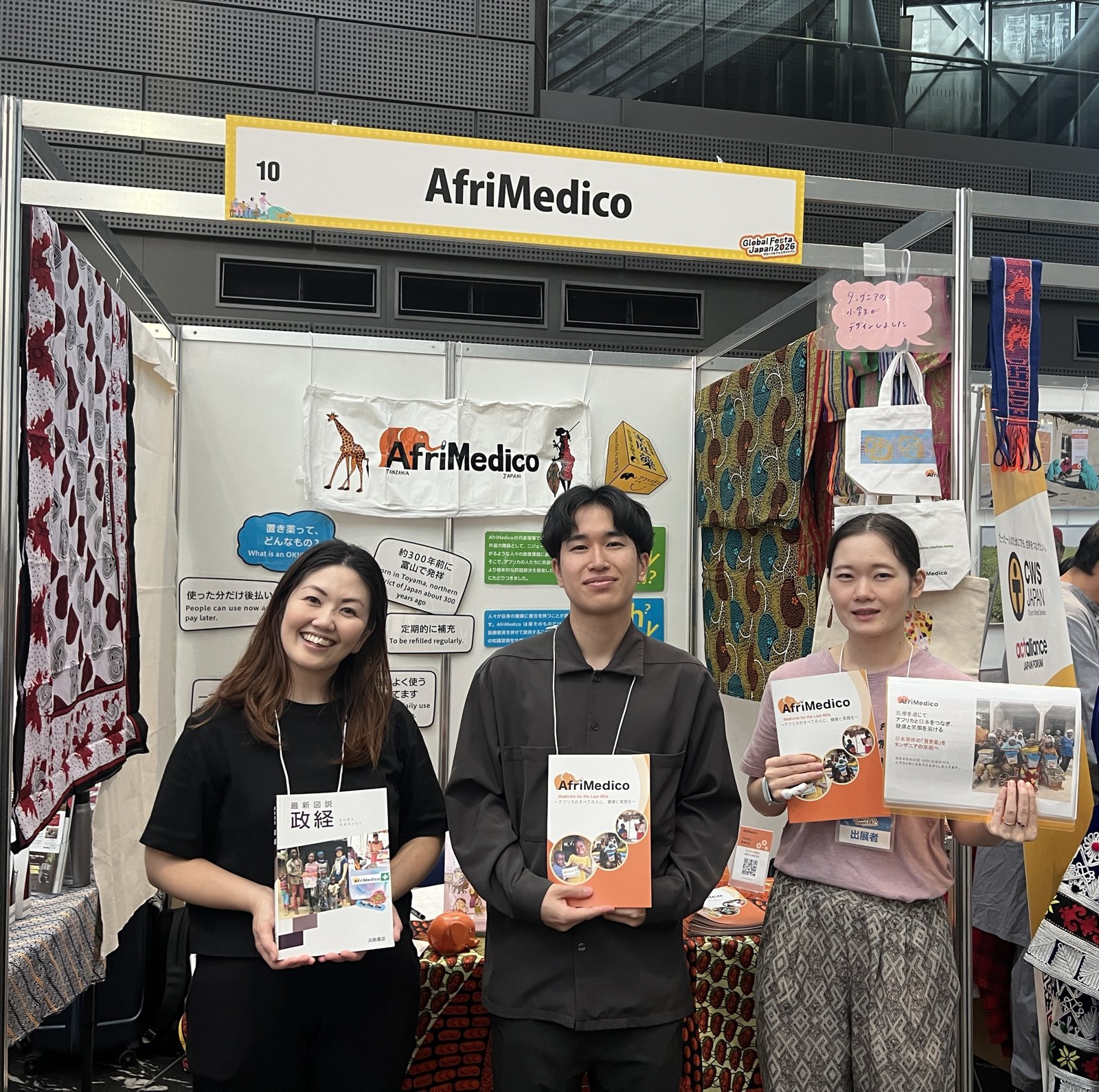 グローバルフェスタJAPAN 2026のAfriMedicoのブース。スタッフ3人がパンフレットを手に並ぶ