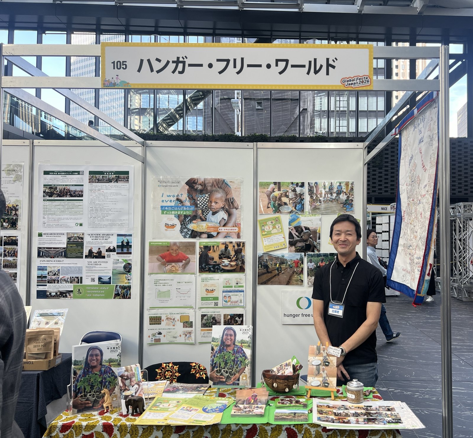 グローバルフェスタJAPAN 2026のハンガー・フリー・ワールドのブース。アフリカの活動写真パネルの前にスタッフが立つ